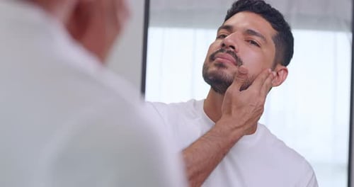 Man Applies Serum to His Face in Mirror
