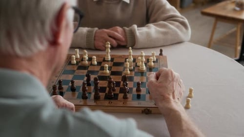 Two Senior Adults Playing Chess Together Indoors