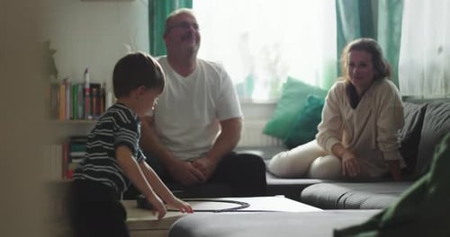 Family Plays with Toy Train Set in Living Room