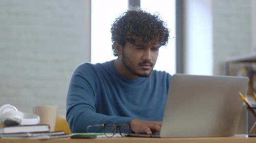 Focused Male Working on Laptop in Modern Workspace During Daytime