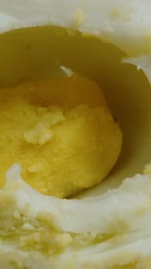 Vertical video. Boiled chicken eggs on a black background, dolly between chopped parts. Close-up.