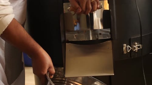 Employee is taking the ready bean to the package area using metal bucket.