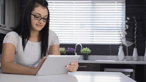 Woman Using Tablet Device in Bright Kitchen Setting