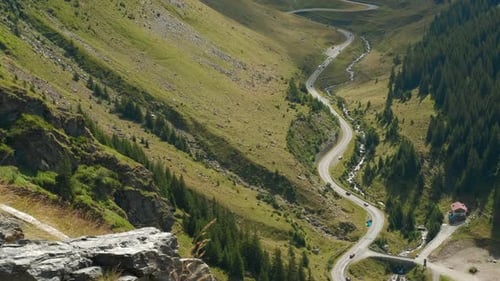 Camera Panning Showing Winding Road Through Mountain Valley with Cars Driving