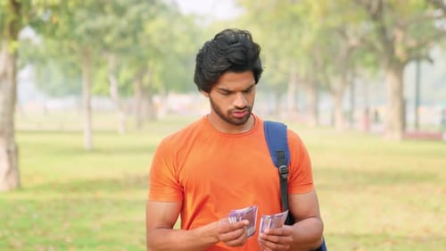 Confused Young Indian Male College Student Counting Money