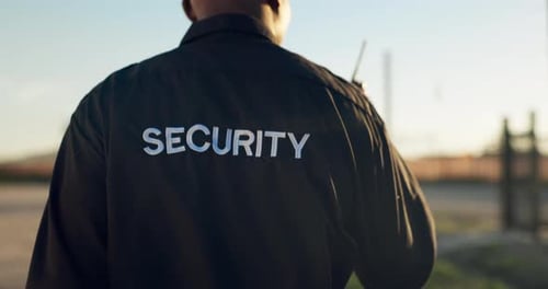 Security Guard Walking with Walkie-Talkie in Urban Setting