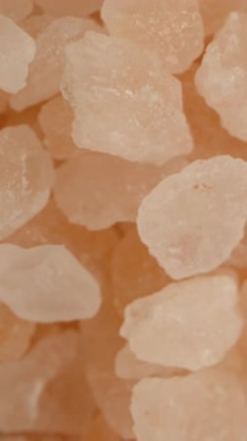 A cluster of pink sea salt crystals, top-down view. Dolly slider extreme close-up. Vertical video.