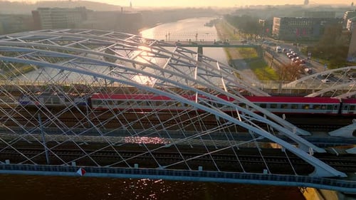 Train Crossing Modern Bridge Over Vistula River in Krakow Poland at Sunset with Cityscape in the