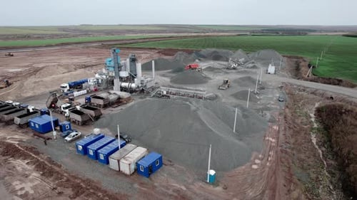 Tippers at Gravel Heaps and Rock Processing Tower in Pit
