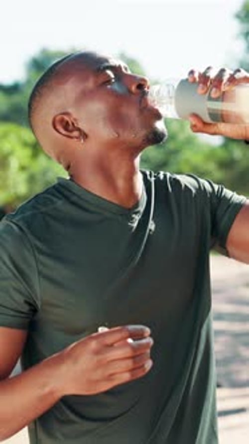 Man Drinks Water From Bottle After Exercising Outdoors