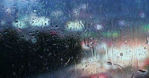 Depuis la fenêtre d'une maison, vous pouvez voir la pluie tomber sur la vitre et le fond flou est