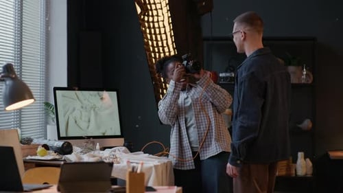 Woman Taking Photo of Man while Working in Studio