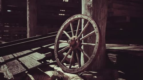 Vintage Wooden Wagon Wheel Resting Against a Weathered Post in an Old Barn