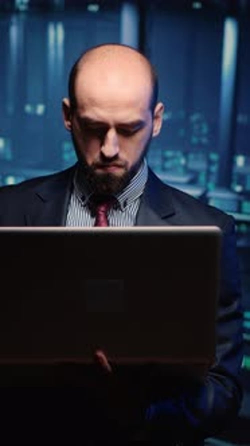 Businessman Working on Laptop in Data Center at Night