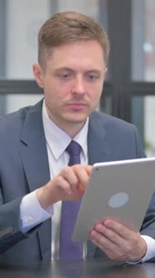Vertical video, Mature Adult Businessman Using Digital Tablet in Office