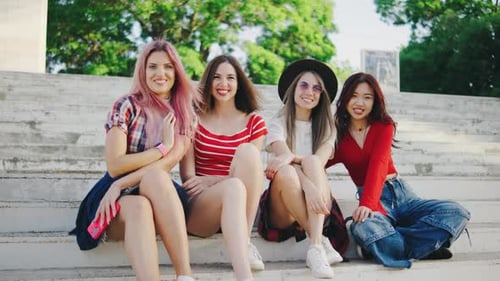 Smiling Young Women Sit Together on Steps