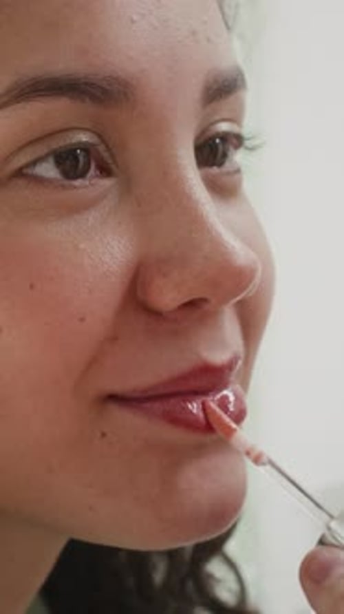 Teenage Girl Smiling while Friend Applying Lip Gloss to Her Lips