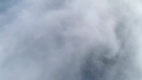 Flug über neblige Wolken im morgendlichen Sonnenlicht mit wenig Glanz und Stadtbild unter Wolken