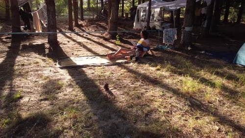 Woman Reading in a Sunny Forest Campsite
