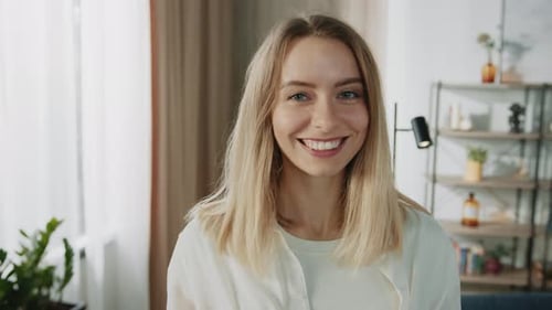 Smiling young woman looks directly at camera indoors