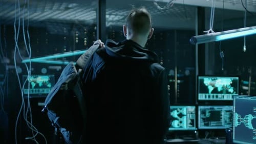 Hooded Hacker ocupa su lugar en su escritorio en Hacker's Lair. El lugar es neón, oscuro y tiene muchos discos