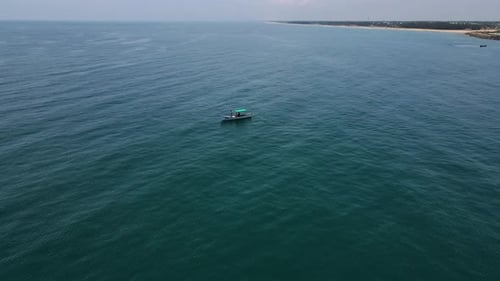 Breathtaking aerial drone shot of a lone fishing boat surrounded by the vastness of the ocean.