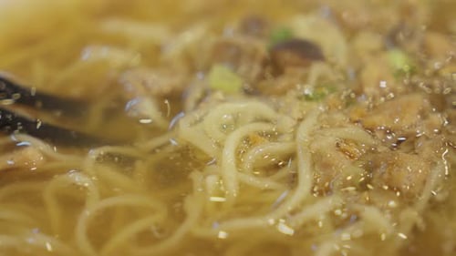 Chopsticks inside asian Bakmi noodle soup. Close up