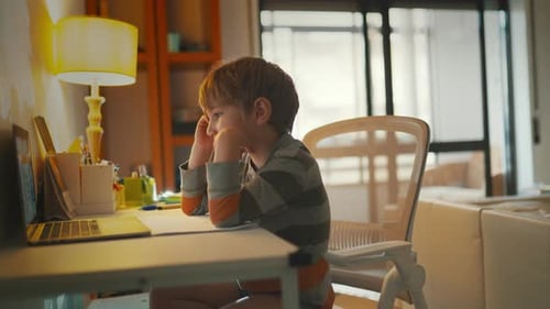 Kind konzentriert sich auf den Laptop, während es am Tisch im Zimmer sitzt