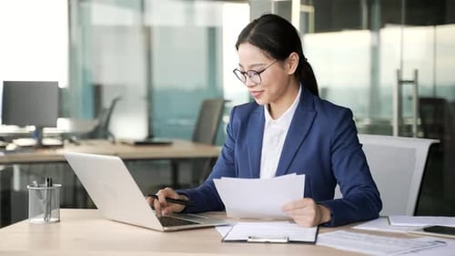 Woman Working on Laptop and Smiling in Office