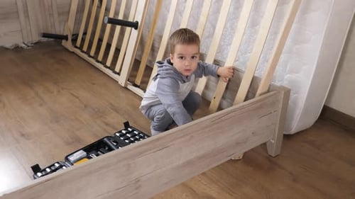 Little Fathers Assistant is Helping to Assemble Wooden Slots of an Orthopedic Base of a Double Bed
