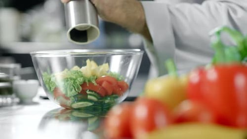 Chef Man Peppering Salad at Kitchen Restaurant. Closeup Chef Hands Peppering Vegetables
