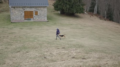 Caucasian Mature Woman with Hat Dressed in Comfortable Clothes and Backpack Walking on the Mountain