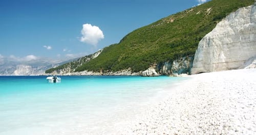 Amazing Fteri beach, Kefalonia, Greece. Pleasure boat in turquoise blue water and white pebble beach