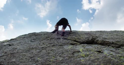 Ein junger Mann klettert auf einen großen Felsen und sucht die Sonne