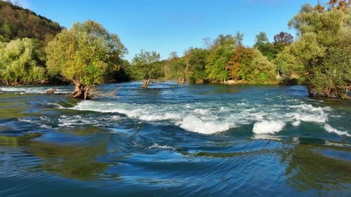 Clean blue water of a mountain river rushing through a green forest on a sunny day. Una river,