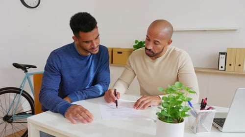 Two Businessmen Reviewing Contract Before Signing in Modern Office