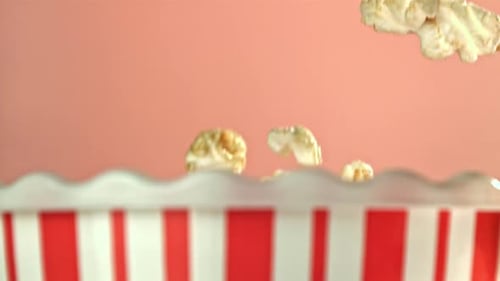 Caramel popcorn falling into a red striped container