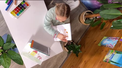 Child Draws in Notebook at Art Table