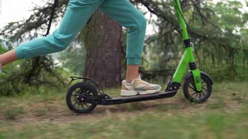 Gros plan des jambes d'une jeune fille sur un scooter Joyeuses promenades en famille dans le parc