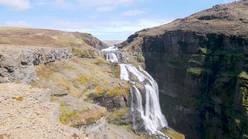 Strong water stream falling down over the Glymur waterfall in Iceland on a sunny day.