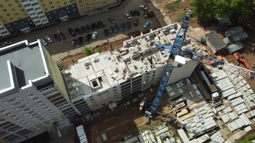 a Crane is on Top of a Building Under Construction in a City Area with Other Buildings and Cars