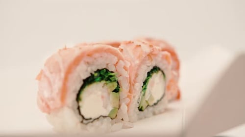 close-up of a roll with baked salmon, cucumber and cheese on a white background in a sushi delivery
