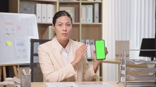 Female Entrepreneur Showing Smartphone with Green Chroma Key Screen to Camera