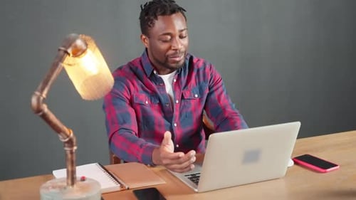 Serious African American Businessman Talking Video Chat on Laptop in Office