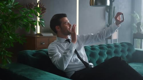 Smiling Man on Video Call While Relaxing on Couch