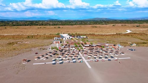 People rest on the sunbeds under umbrellas on the beach of the Adriatic Sea.