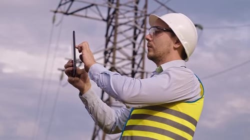 Engineer Using Tablet by Electrical Transmission Tower