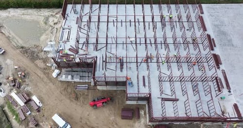 Industrielle Baustelle mit Arbeitern bei der Montage eines Metallrahmengebäudes, Entwicklung von Wohngebäuden