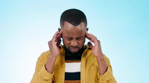 Black man, headache and massage temple with stress or burnout in studio with pain on blue