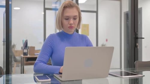 Young Woman Works on Laptop in Modern Office